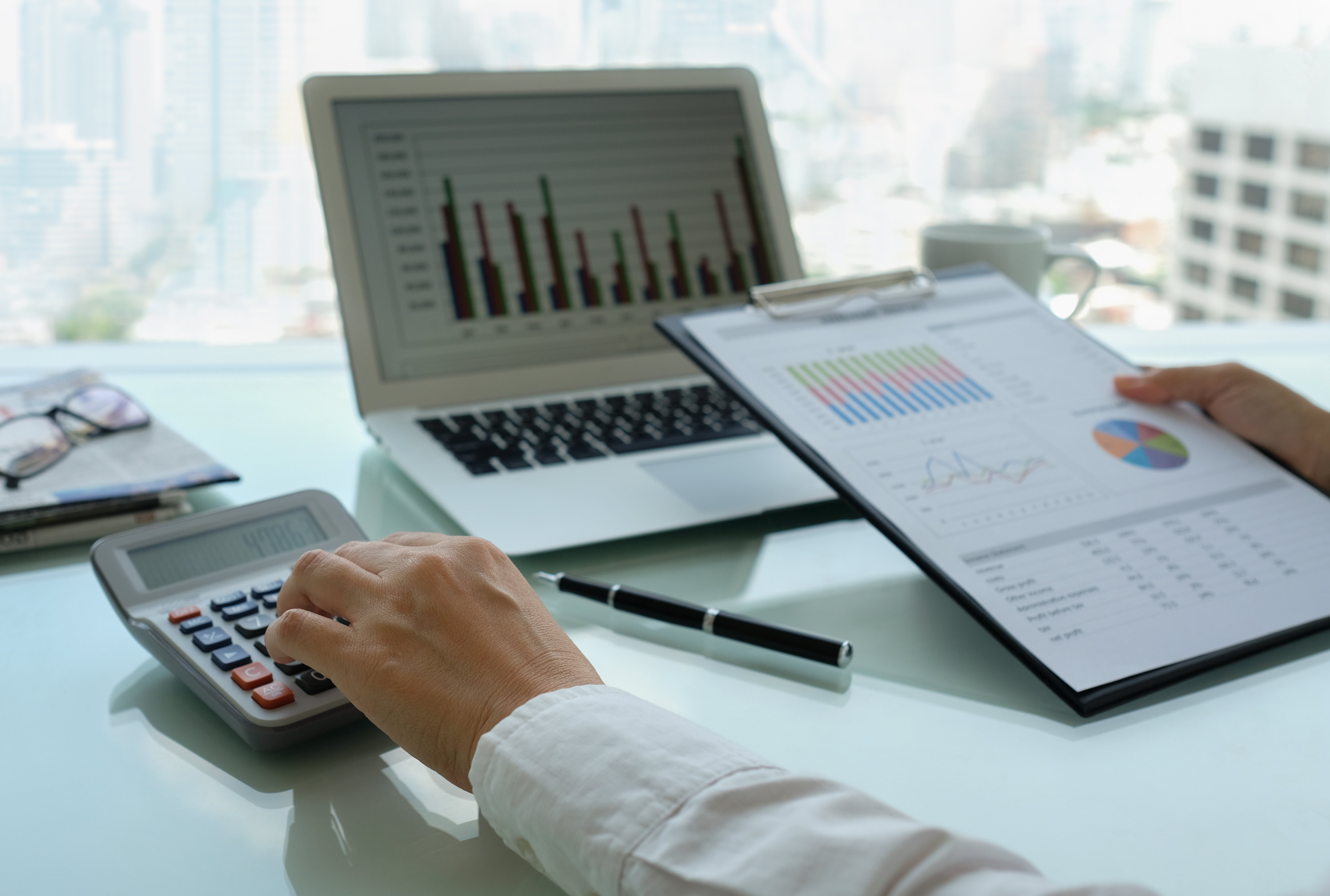 Accountant at work using a laptop, clipboard and calculator
